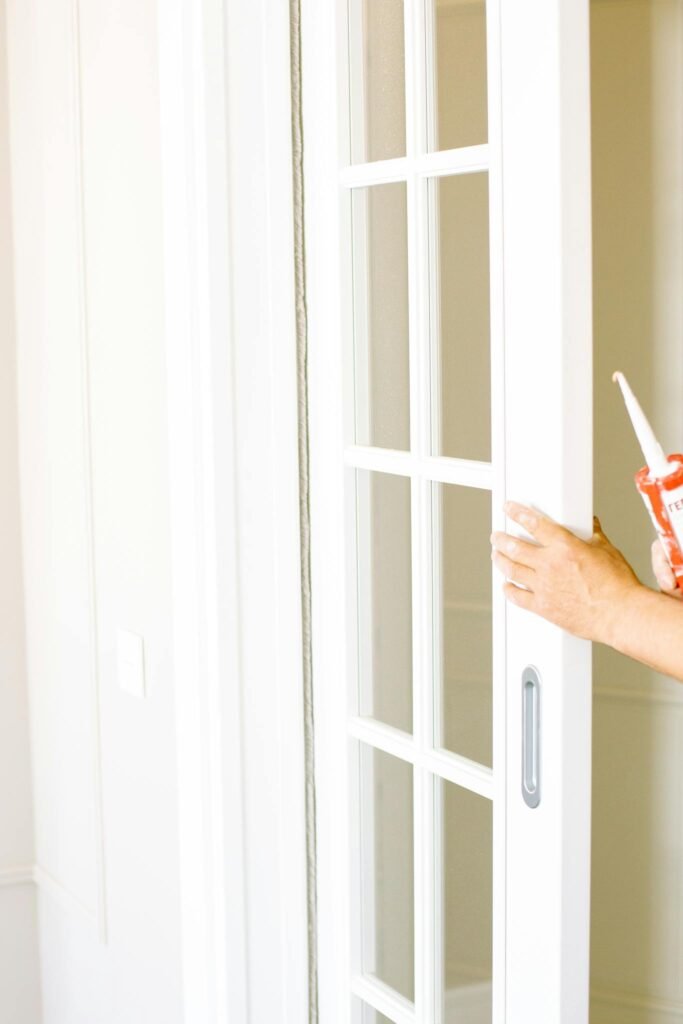 Person applying putty to a sliding door during home renovation indoors.